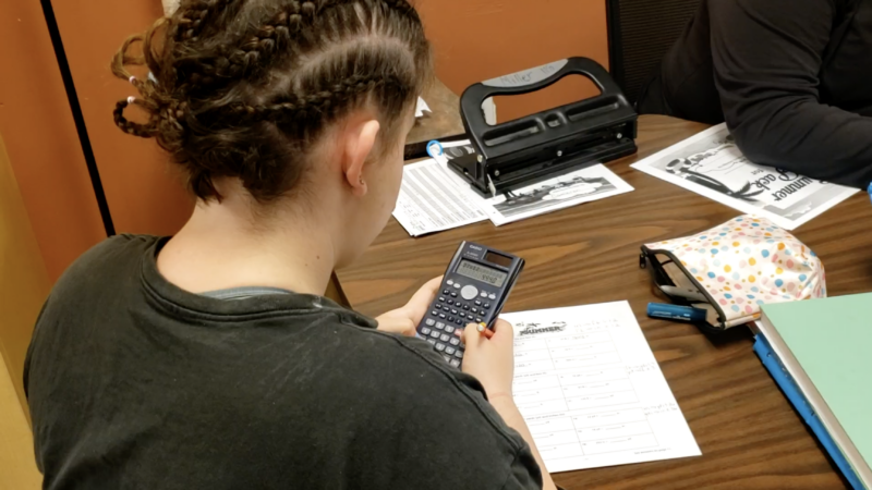 Home of the Innocents work in action. A student works on homework with their calculator.