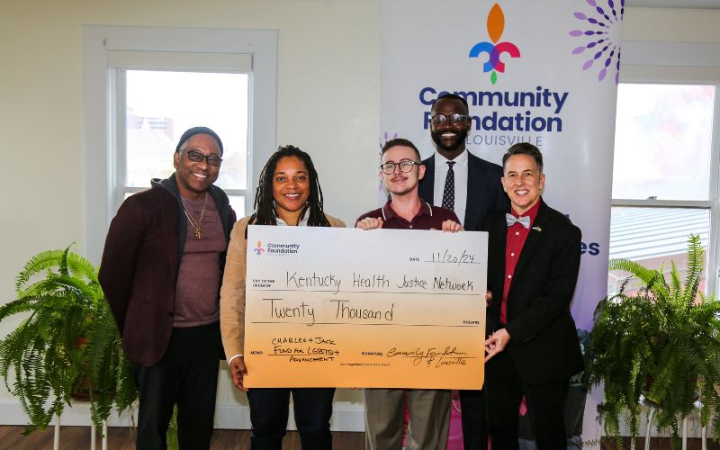 group of people smiling and holding a check